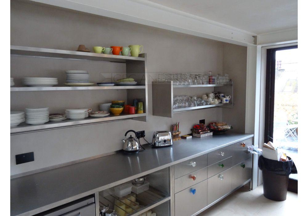 Custom stainless steel shelving combined with stainless steel wall cabinet. Stainless steel worktops and base units below.